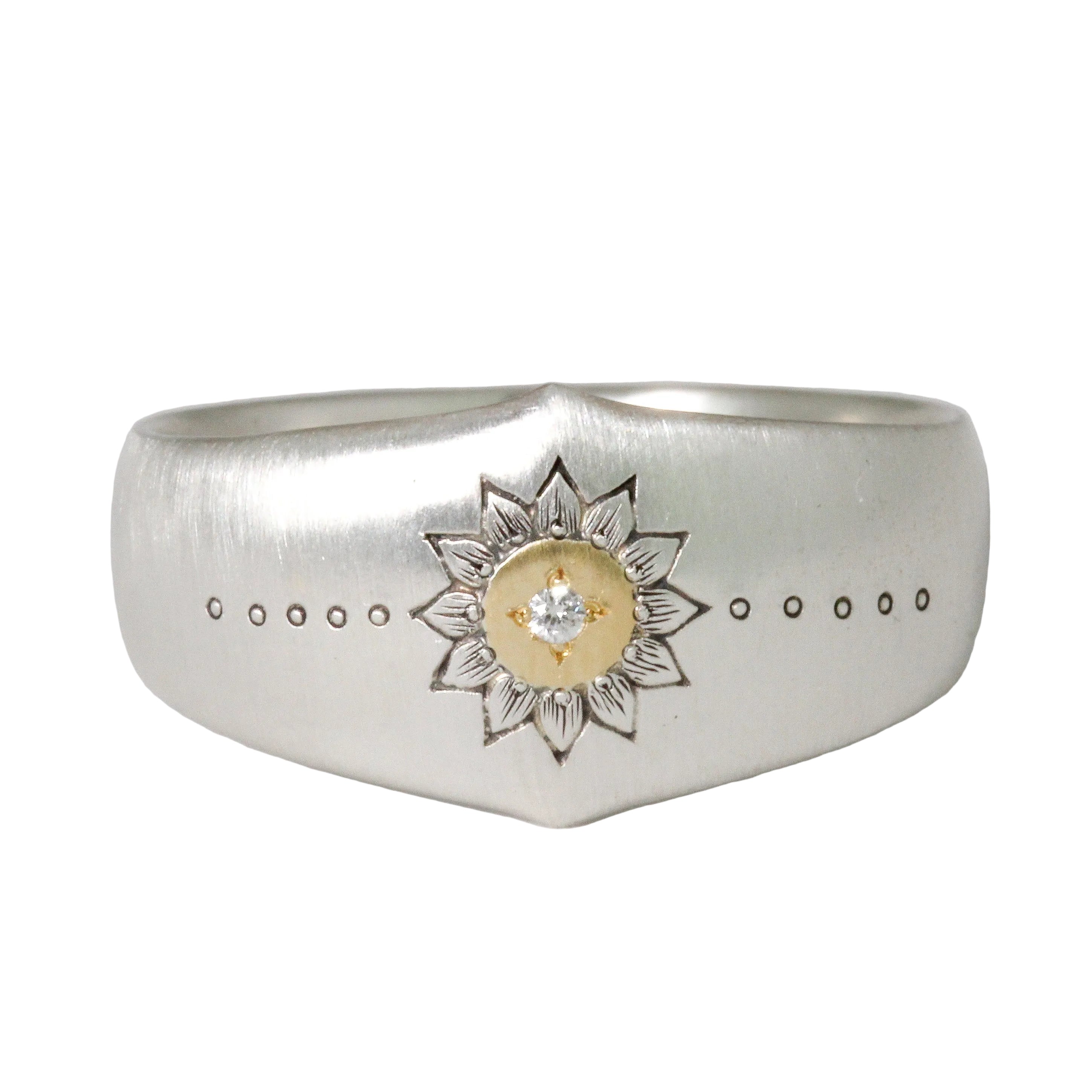 Silver ring with a floral design and gold center on a light gray background