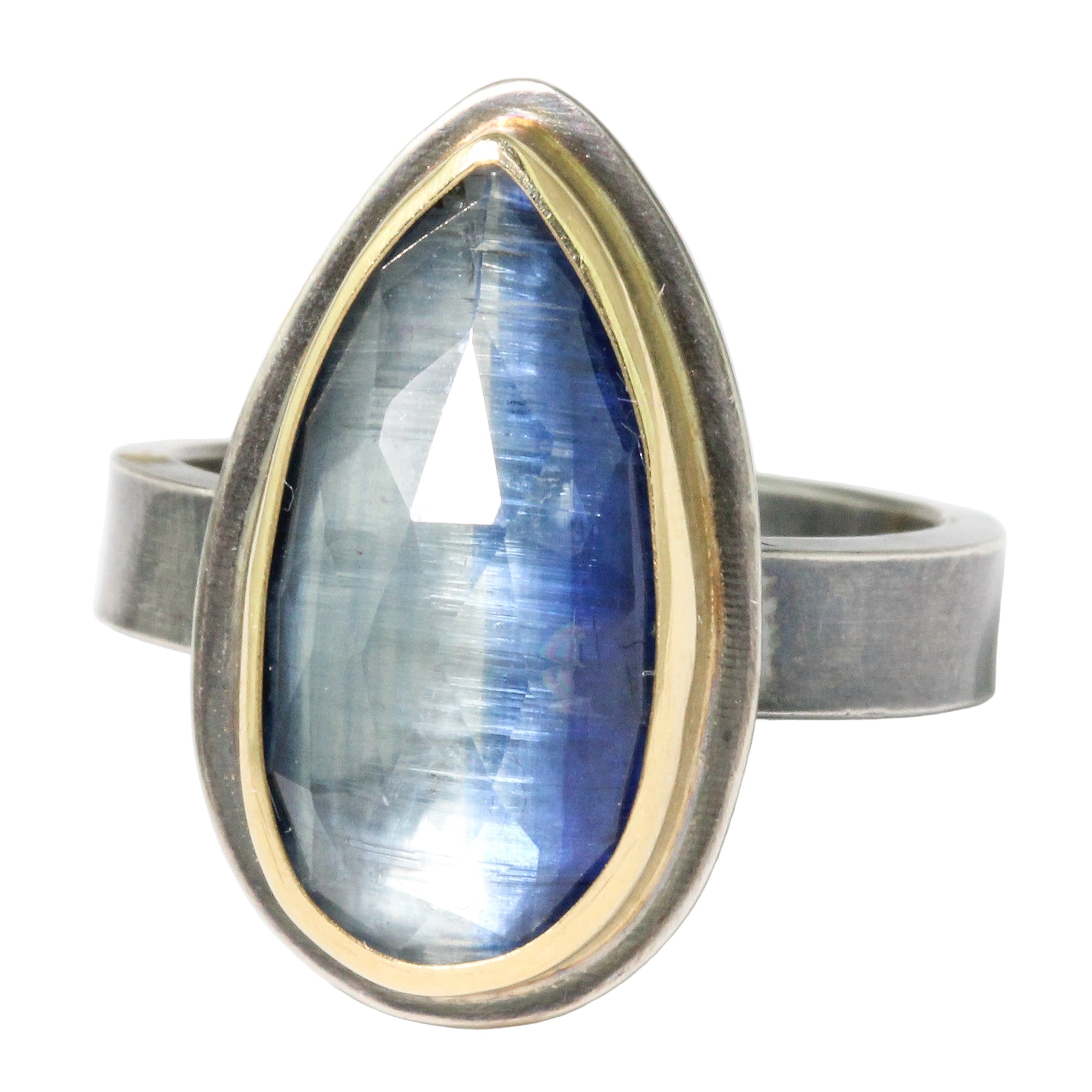 Ring with a blue teardrop-shaped gemstone and gold and silver band on a white background