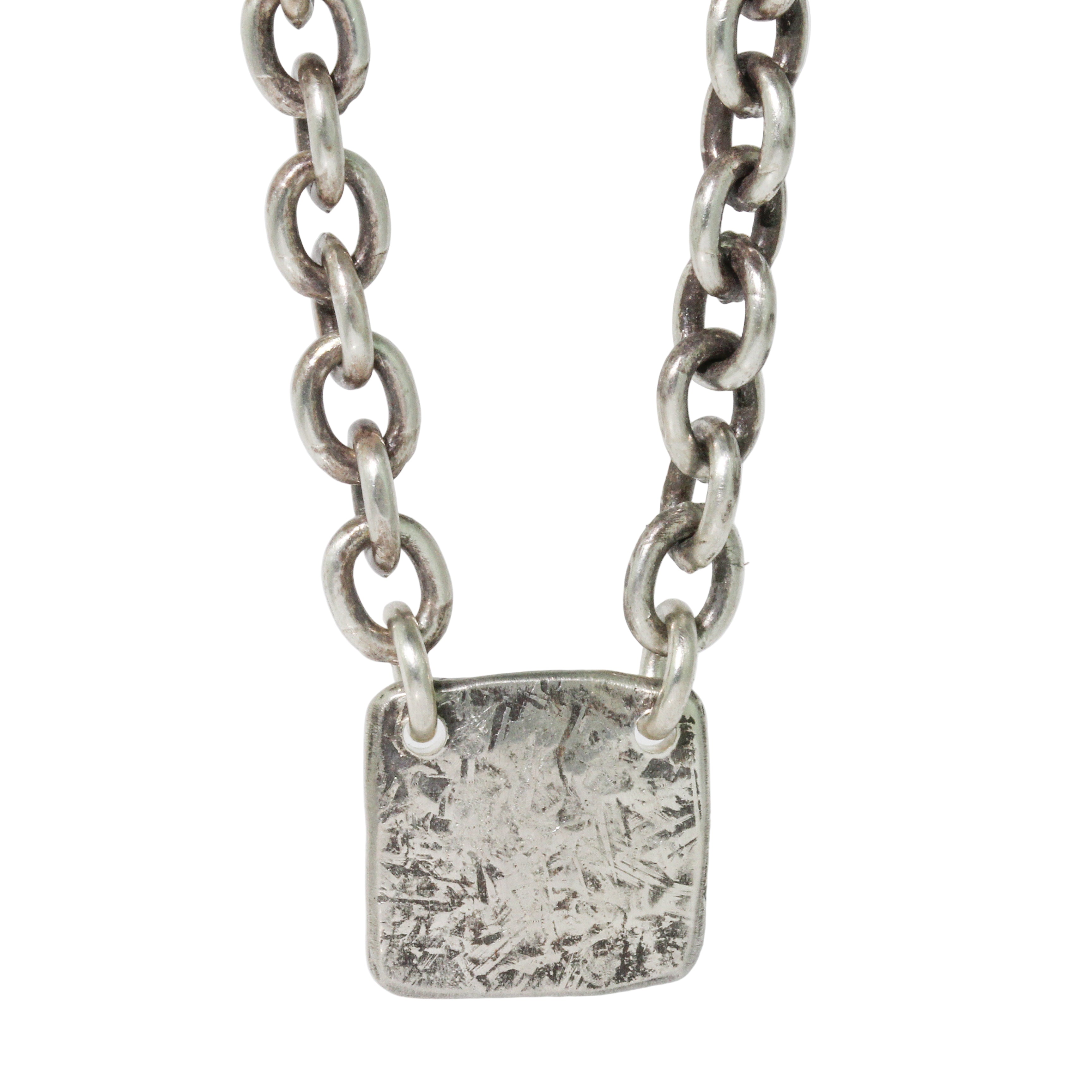 Silver chain necklace with a textured square pendant on a light gray background