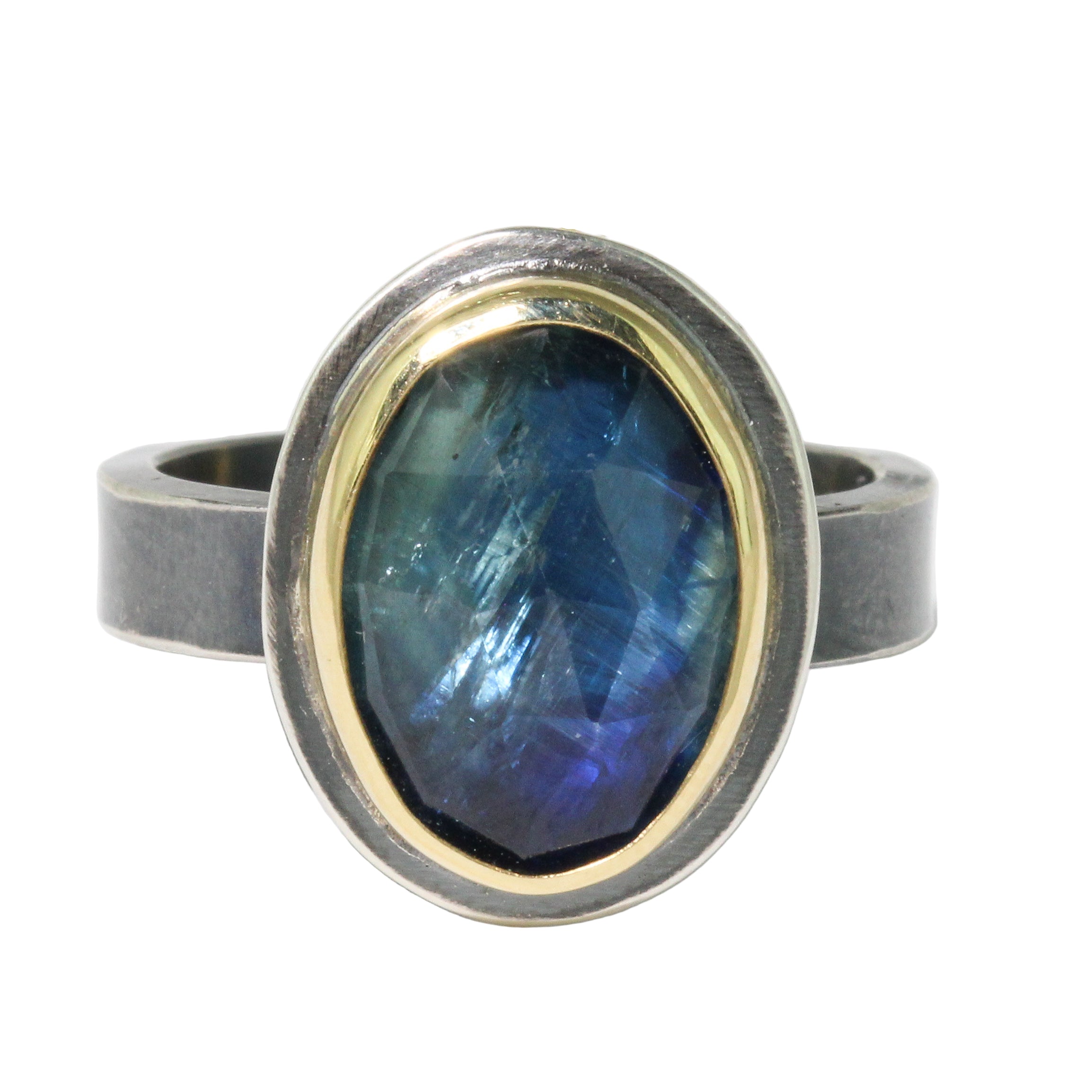 Ring with a blue gemstone and two-tone metal band on a white background